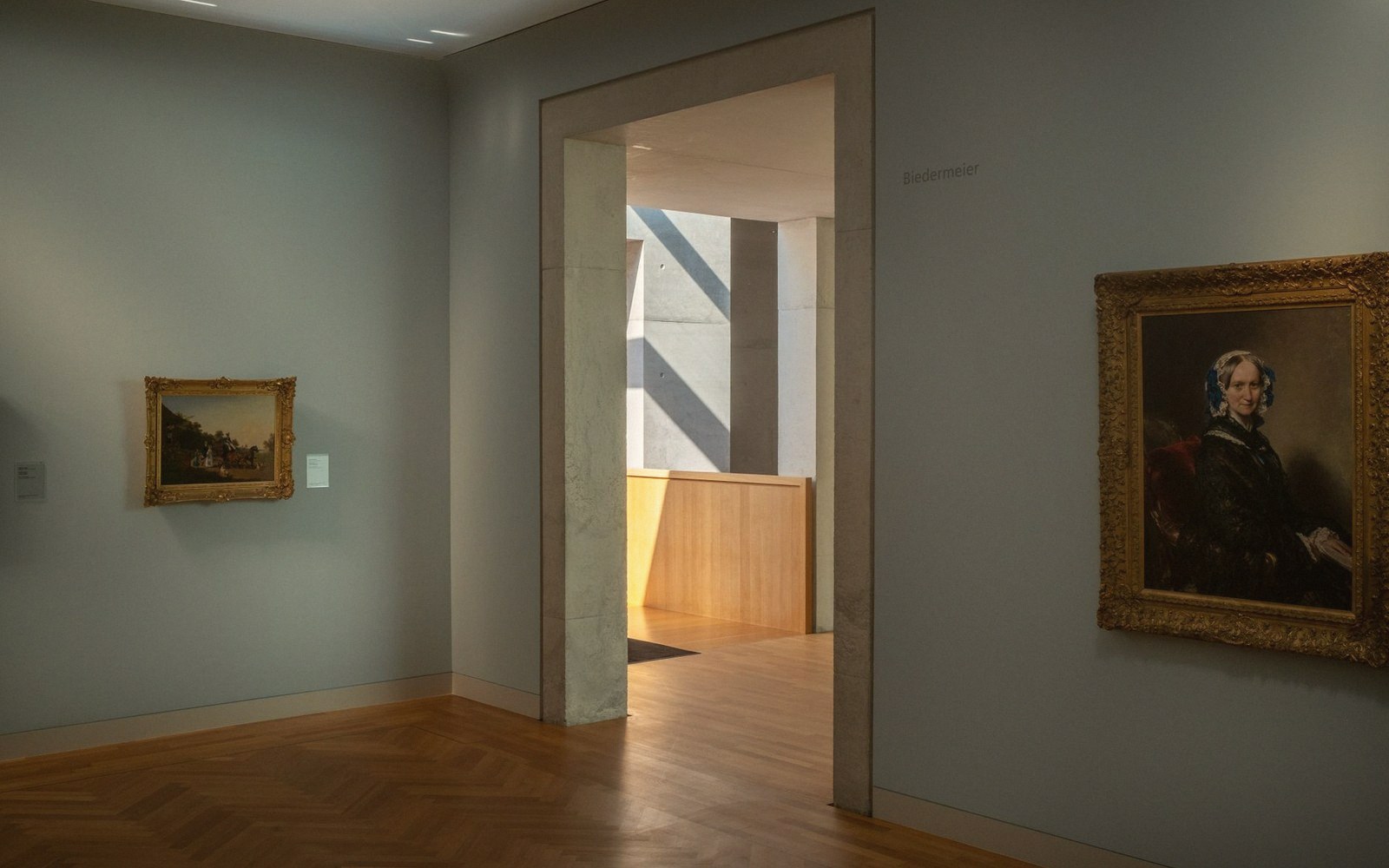 Gilt-framed portraits flank a doorway leading into a sunlit Biedermeier gallery