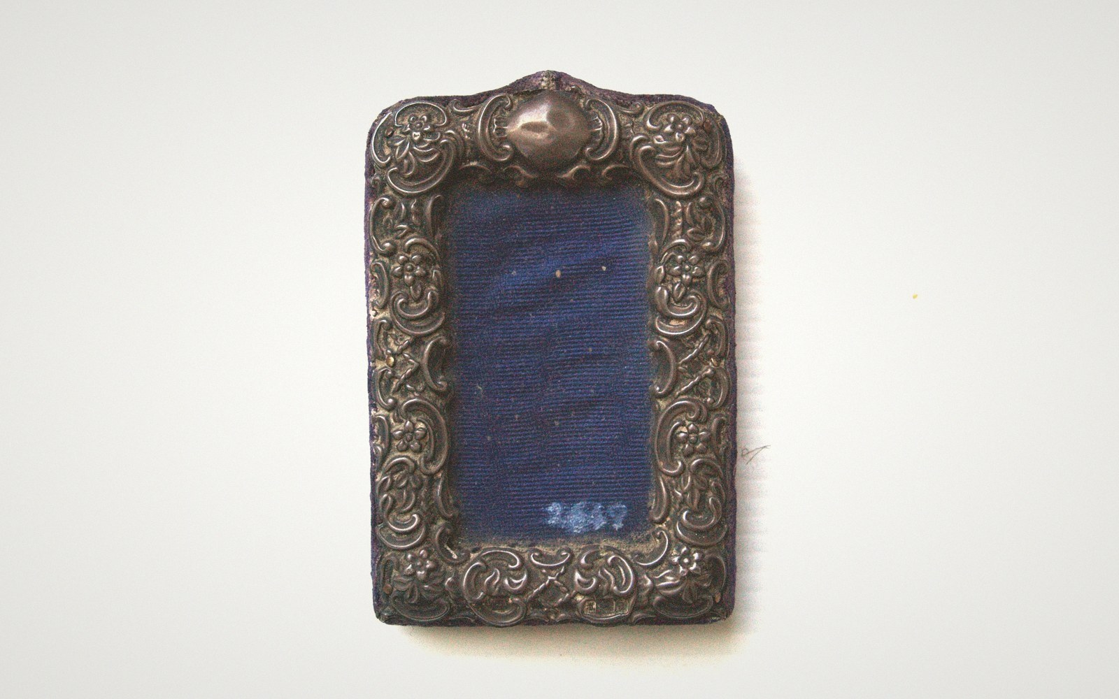 Ornate silver picture frame with floral repoussé work and blue velvet insert, empty